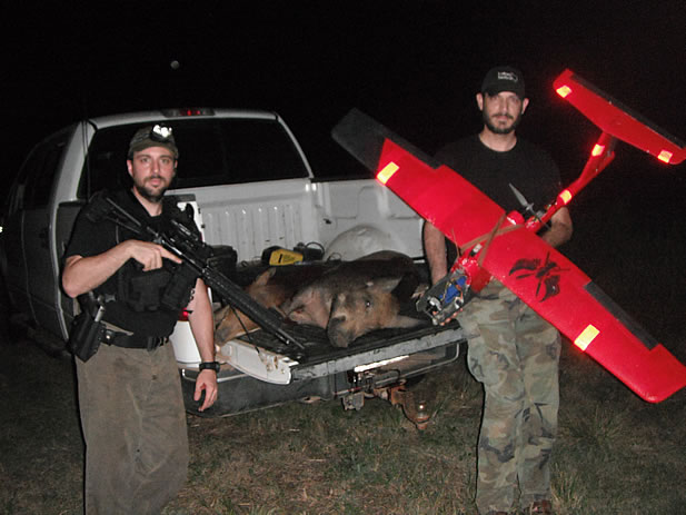 hunters pose with a drone and a dead hog in a truck
