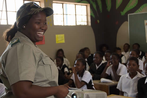 photo of a woman in a khaki uniform in front of a classroom full of children